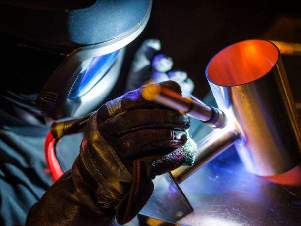A man using a TIG (Tungsten Inert Gas) welder in a workshop.